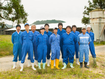 写真：青いツナギを着て並んでいるヤマモトのスタッフ